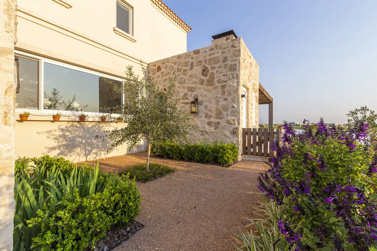 fachada rústica moderna con piedra, ventanas amplias y vegetación — proyecto Casa MF, por Estudio Junor, en Belén de Escobar
