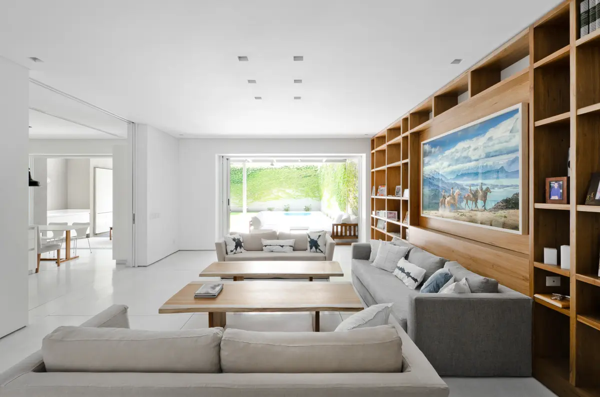 Living moderno con estantería de madera y luz natural — proyecto Casa D, por Estudio Dado, en Belgrano