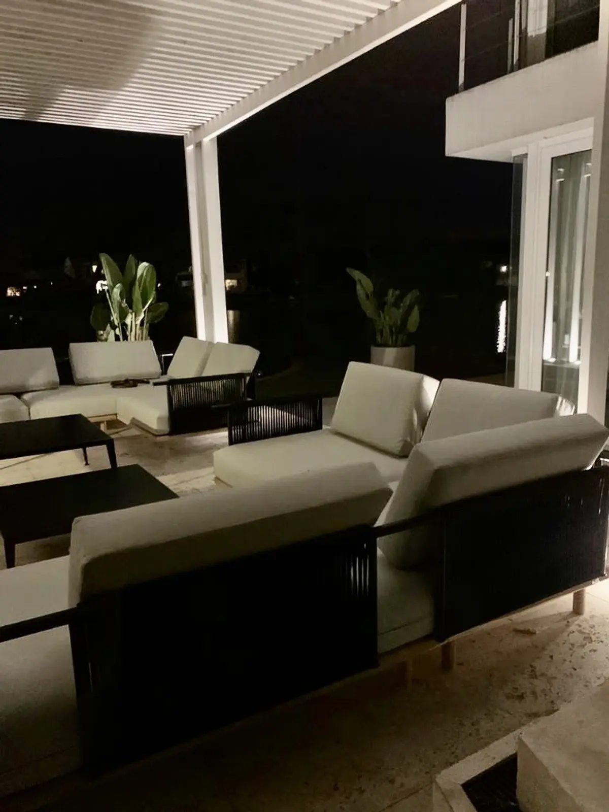 Patio moderno de noche con sofá modular y pérgola — proyecto CASA LAGUNA, por Estudio Xime Fontan Balestra, en Tigre