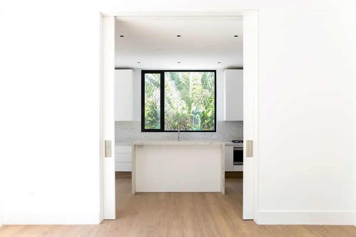 Cocina moderna con isla, muebles blancos y grandes ventanales — proyecto Bosque Chico, por Estudio Arq. María Sioli, en Garin