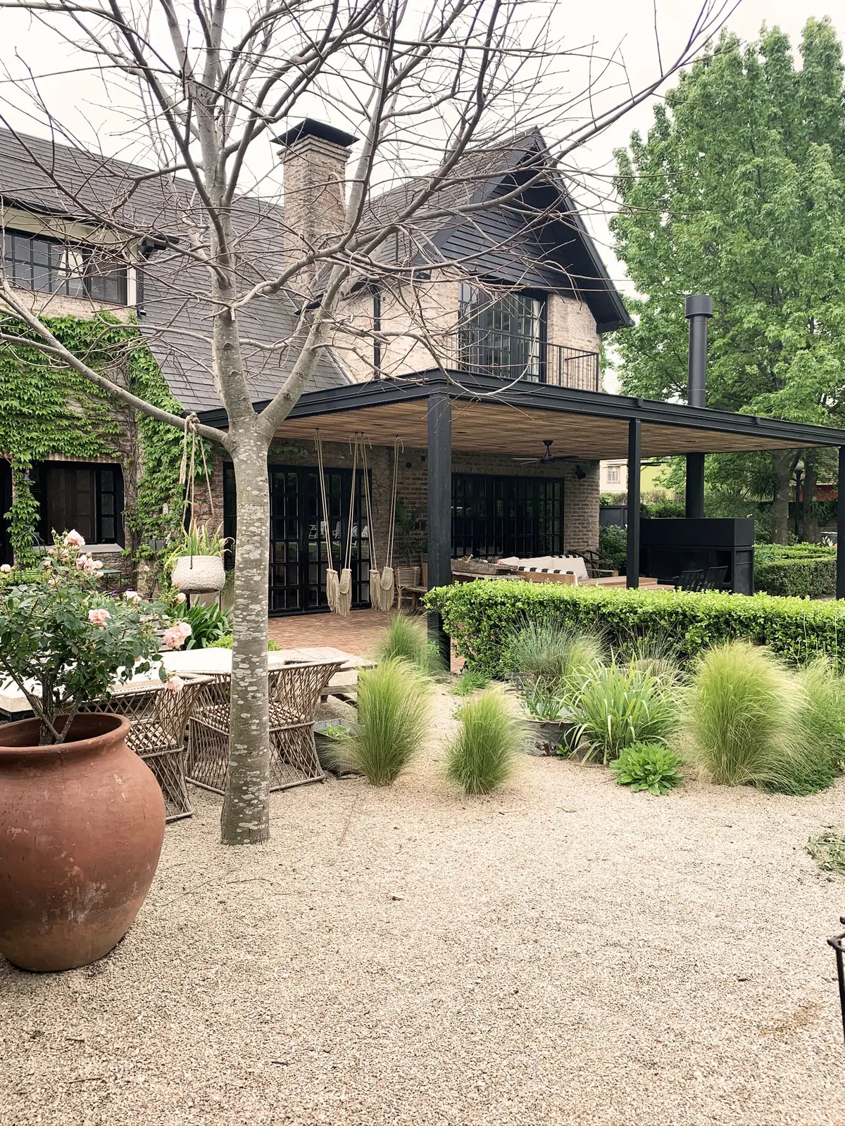 Casa de tijolo com pérgola, pátio de cascalho e churrasqueira ao ar livre — projeto Monroe - La Horqueta, por Mgc.arq, em La Horqueta