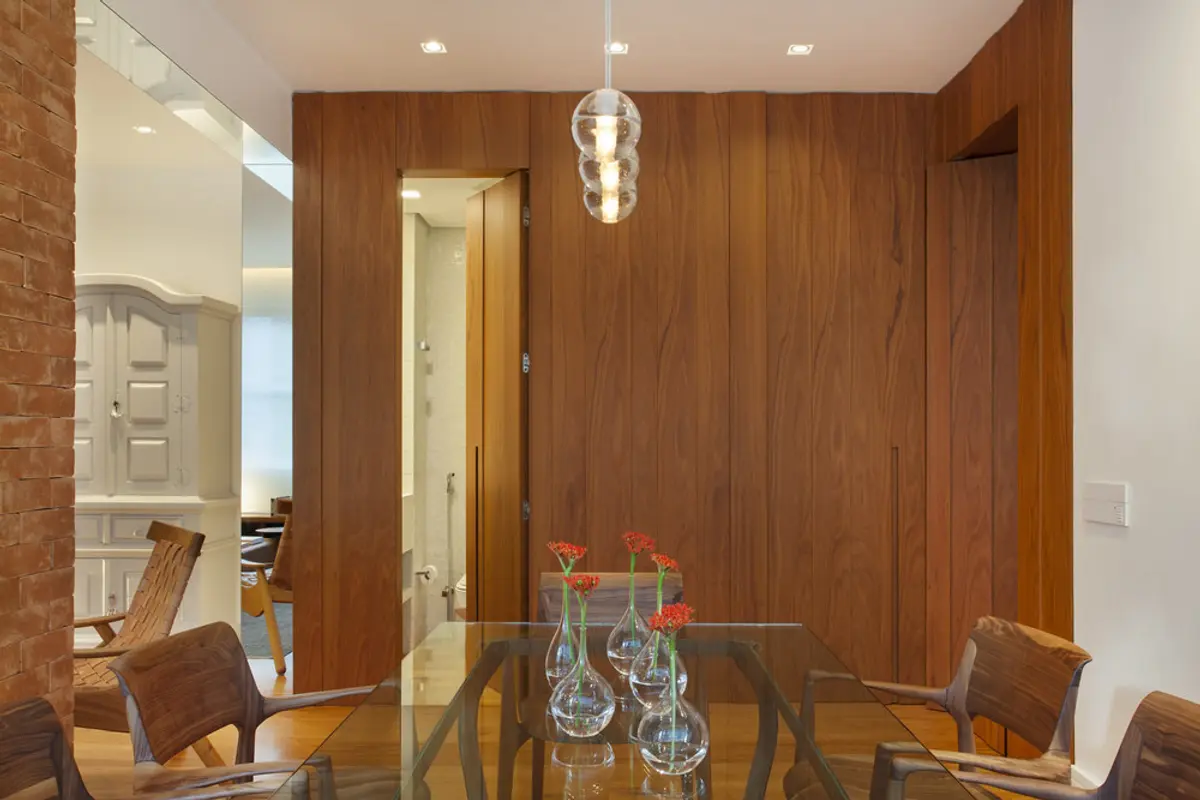 Comedor moderno con pared de madera, mesa de vidrio y lámpara colgante — proyecto MS House, por Studio Ro-ca