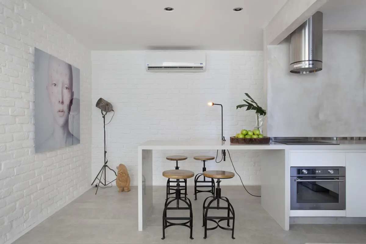 Cocina minimalista blanca con isla, taburetes negros y ladrillo visto — proyecto RF House, por Studio Ro-ca