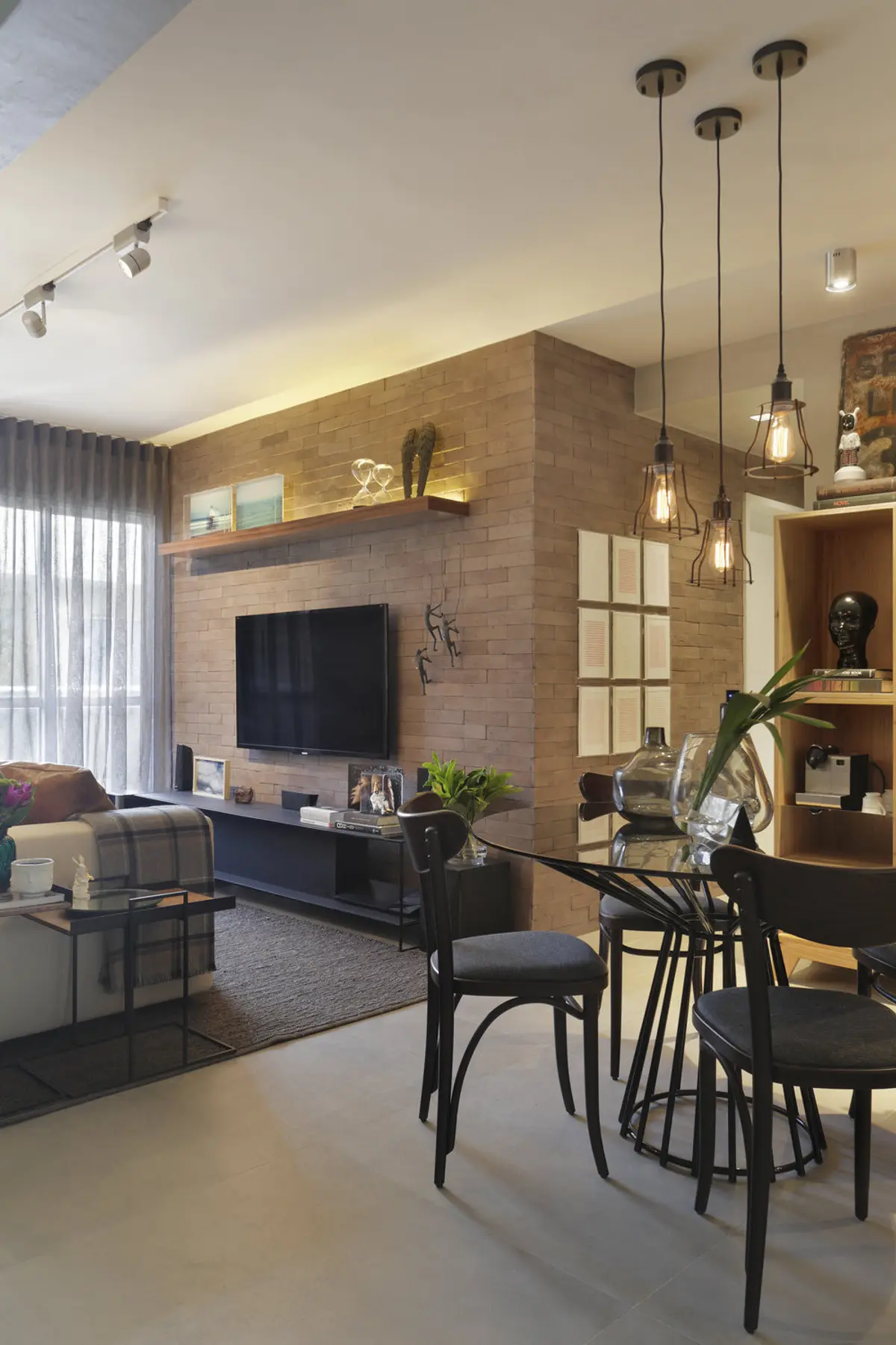 Living comedor con ladrillo visto, muebles negros y cálidas luces colgantes — proyecto SC House, por Studio Ro-ca