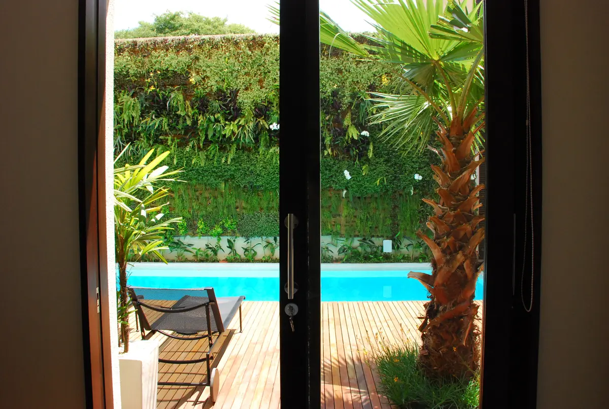 Pileta turquesa con deck de madera y palmera en jardin verde — proyecto Residência EC, por Gil Fialho