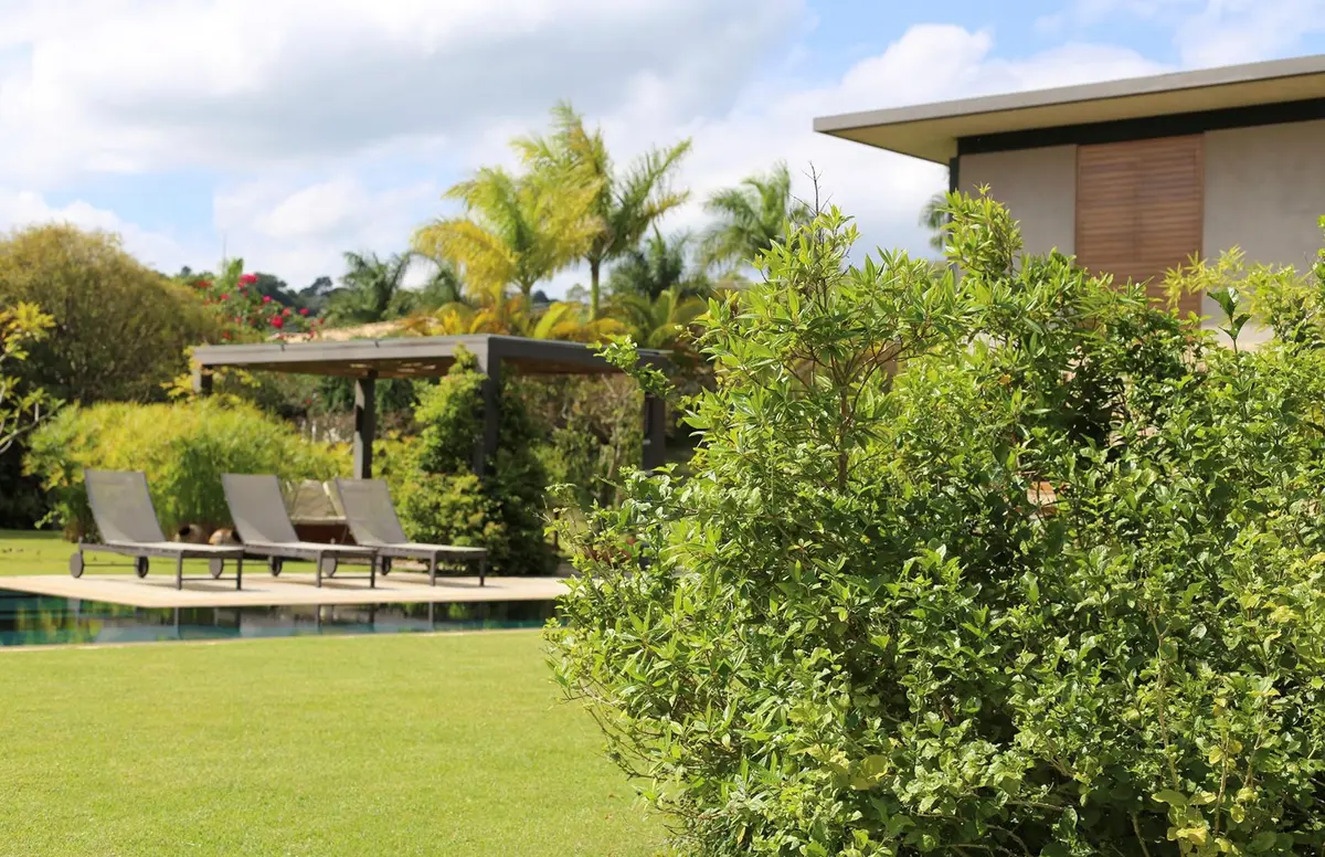 Jardín con pileta, deck de madera y pérgola frente a casa moderna — proyecto Residencia PZ, por Gil Fialho