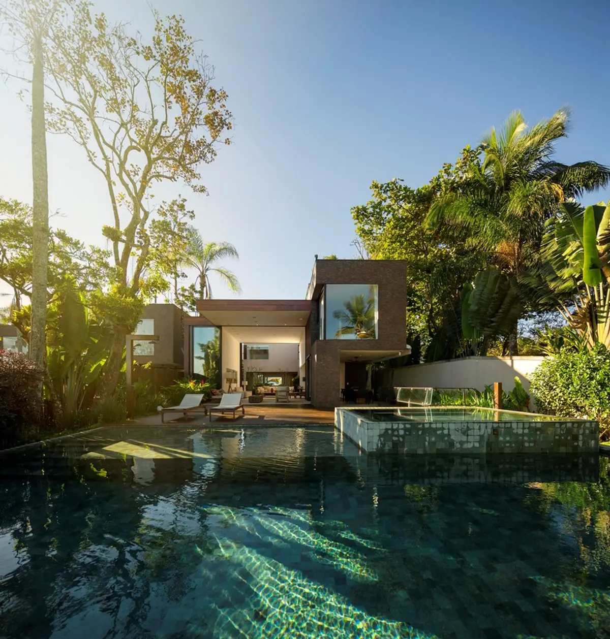 Casa moderna con pileta y jardín tropical al atardecer — proyecto West Whales, por Gil Fialho