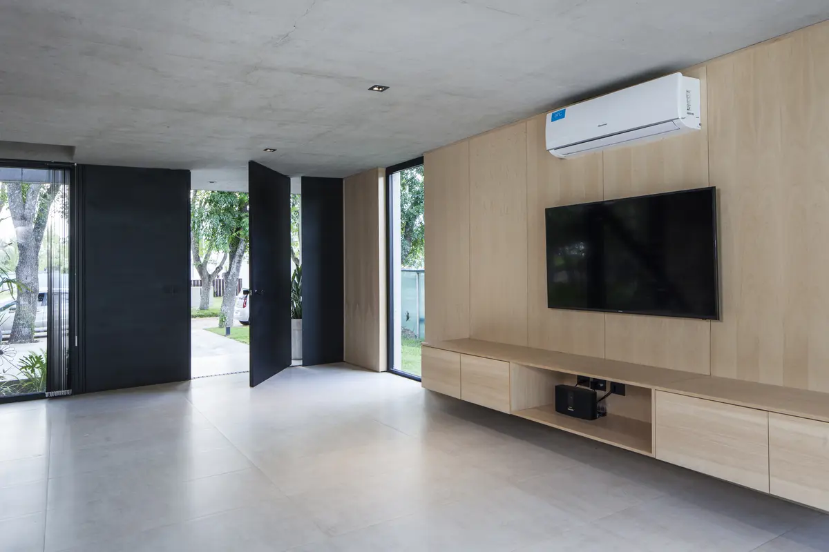 Sala de estar moderna com paredes de madeira e concreto — projeto Black House, por V2 Arquitectos, em City Bell