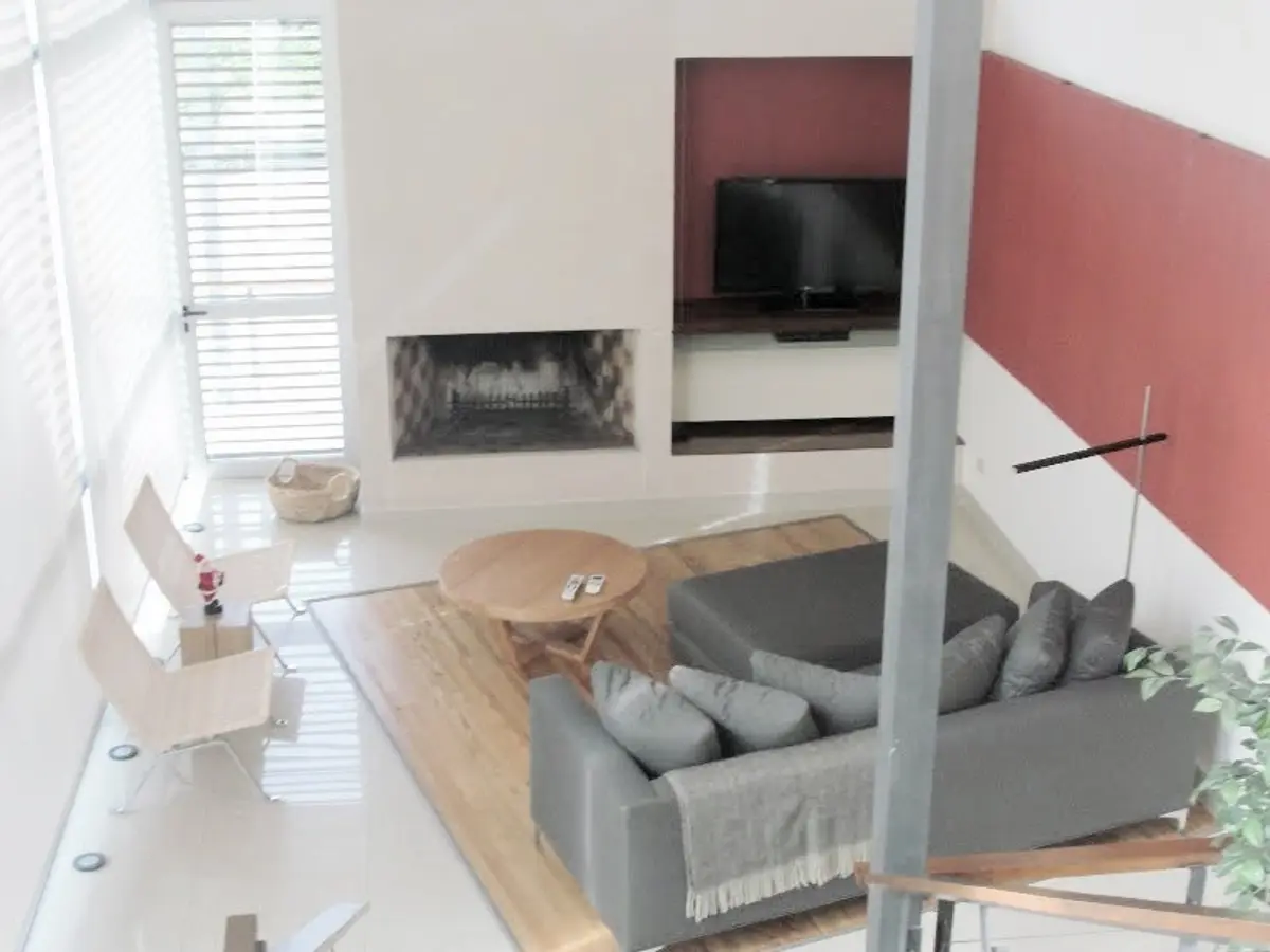 Living moderno de doble altura con chimenea y pared de madera — proyecto Proyecto MH, por Vicky Hurrell, en Mar del Plata