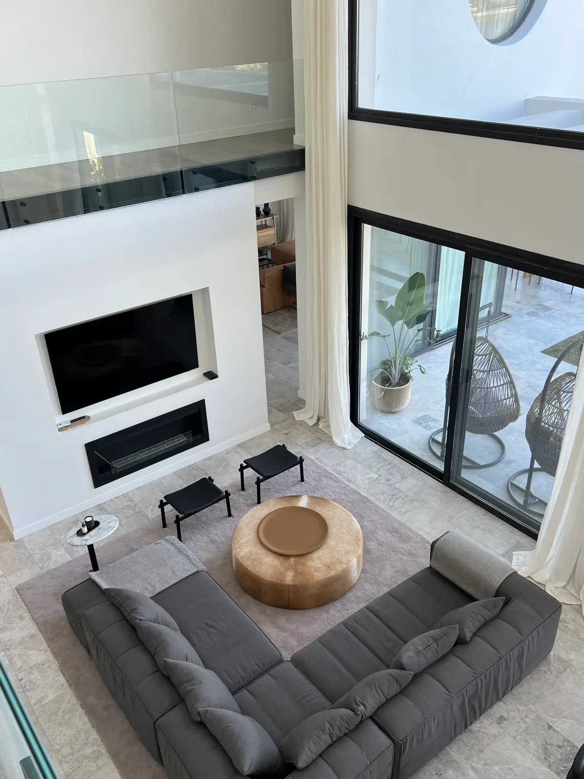 Living doble altura con sofá modular gris, mesa madera y chimenea blanca — proyecto CASA LR427 - SOFITEL LOS CARDALES, por Carolina Depetris, en B2814 Los Cardales