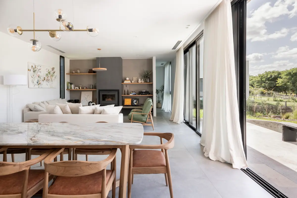 Sala de estar e jantar moderna aberta com vista rural e mesa de mármore — projeto Casa San Matías, por BK Arquitectos, em Belén de Escobar
