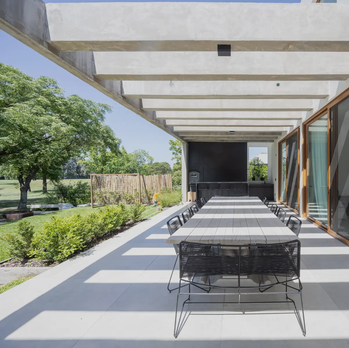Patio moderno con pérgola de hormigón y vegetación exuberante — proyecto CASA BaCa, por Alfredo Orfila arquitectura, en Benavidez