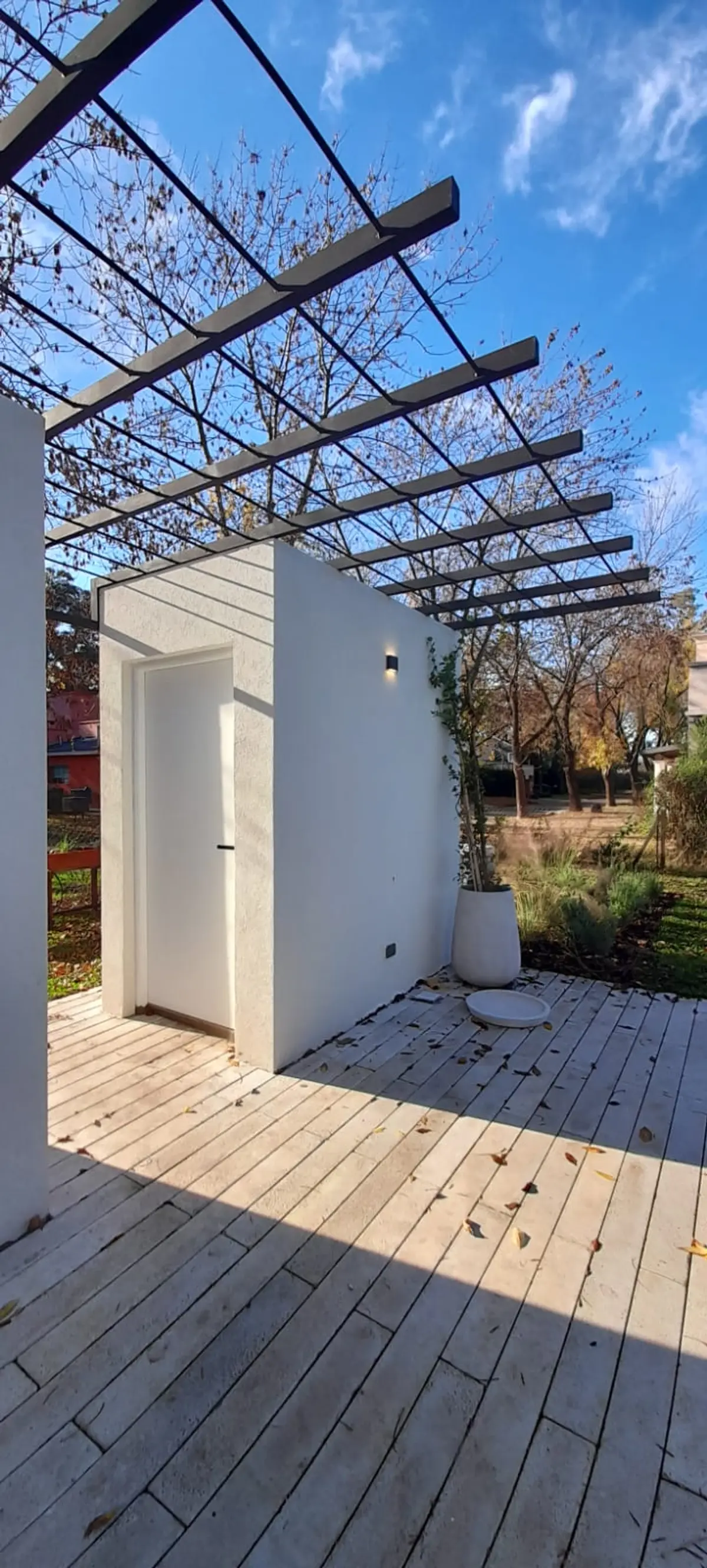 Pátio moderno com pergolado e deck de madeira — projeto El 54, por Valeria Damiani Arquitecta, em Pilar