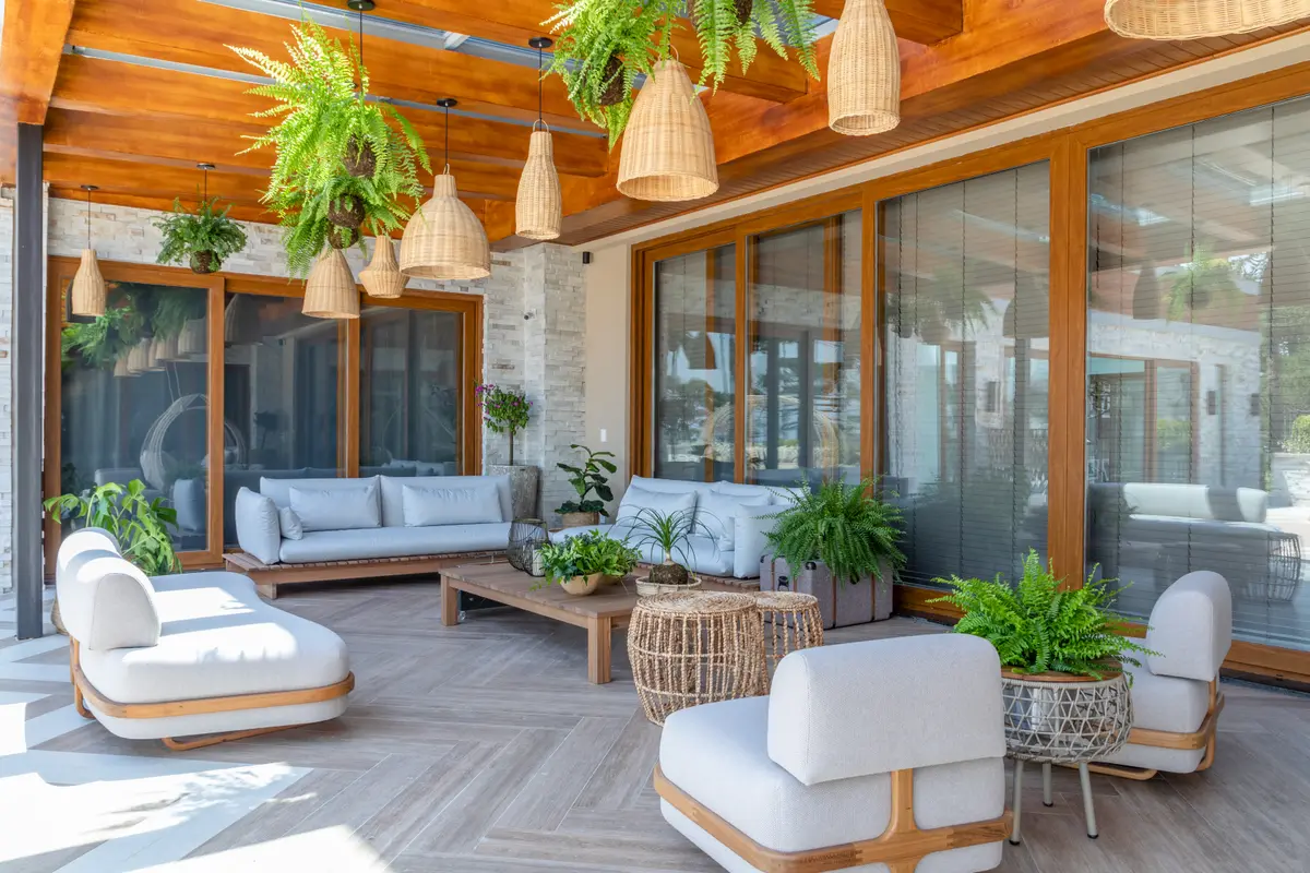 Terraço semi-externo com pérgola de madeira, móveis de vime e grandes janelas — projeto Projeto Destaque Club&Casa, por OKA ARQUITETURA