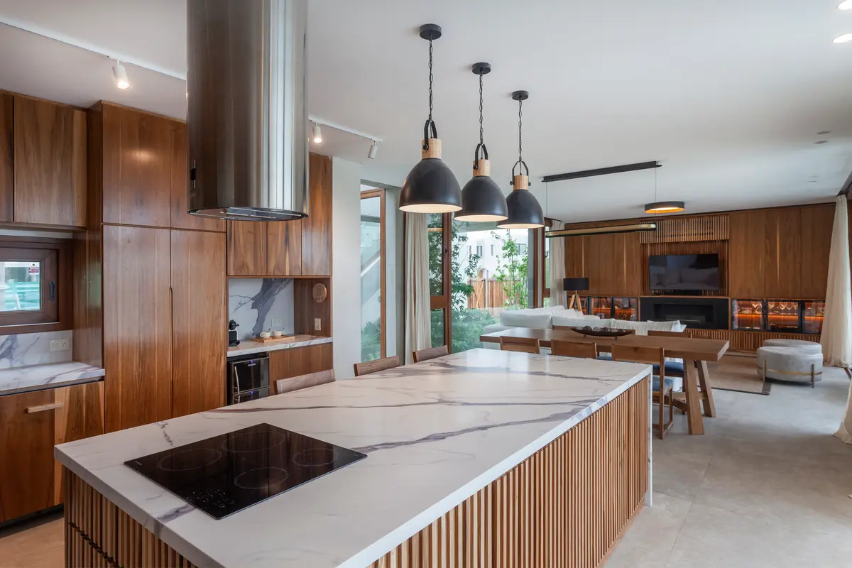 Cozinha moderna integrada com ilha de mármore e detalhes em madeira — projeto Casa Boating, por LSA., em Belén de Escobar