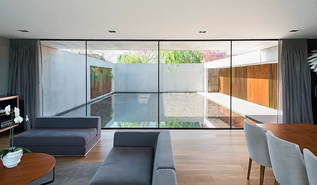 Sala de estar moderna com piscina interna e grandes janelas de vidro — projeto Casa Lefebvre, por Estudio Ramos