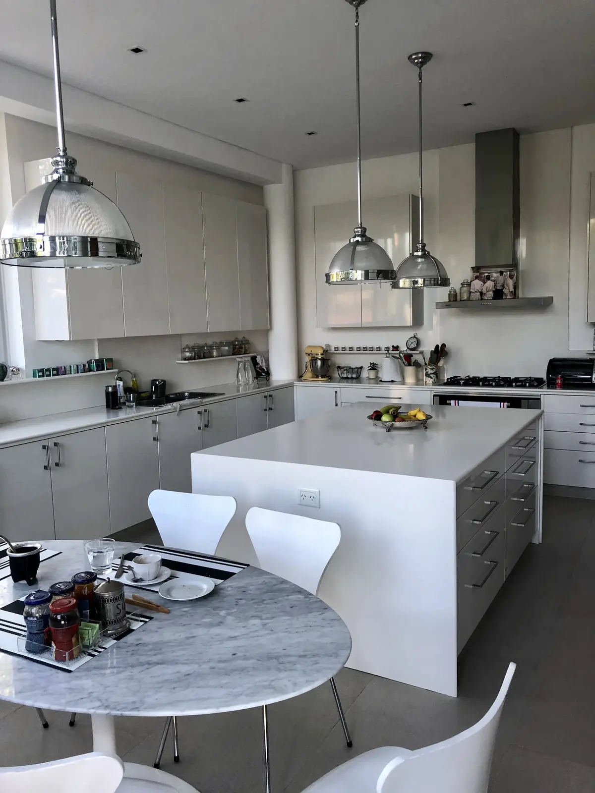 Cocina moderna con isla, mesa de mármol redonda y sillas blancas — proyecto CASA LAGUNA, por Estudio Xime Fontan Balestra, en Tigre
