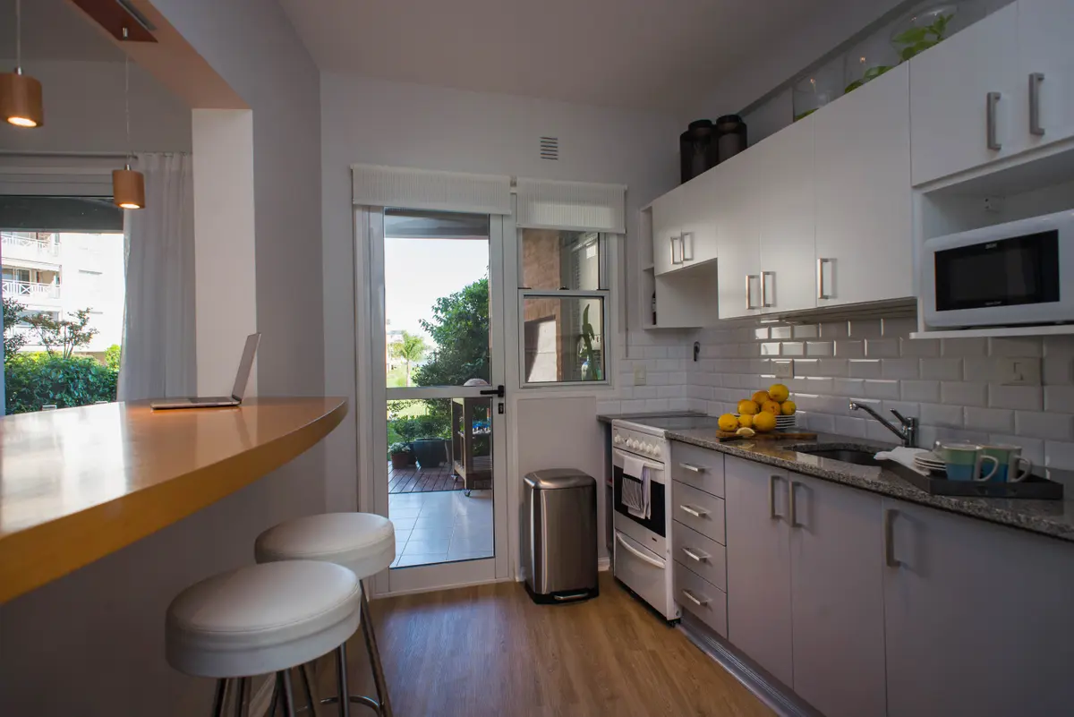 Cocina moderna blanca con barra y electrodomésticos integrados — proyecto Casa en Nordelta, por Gutman+Lehrer Arquitectas, en Nordelta