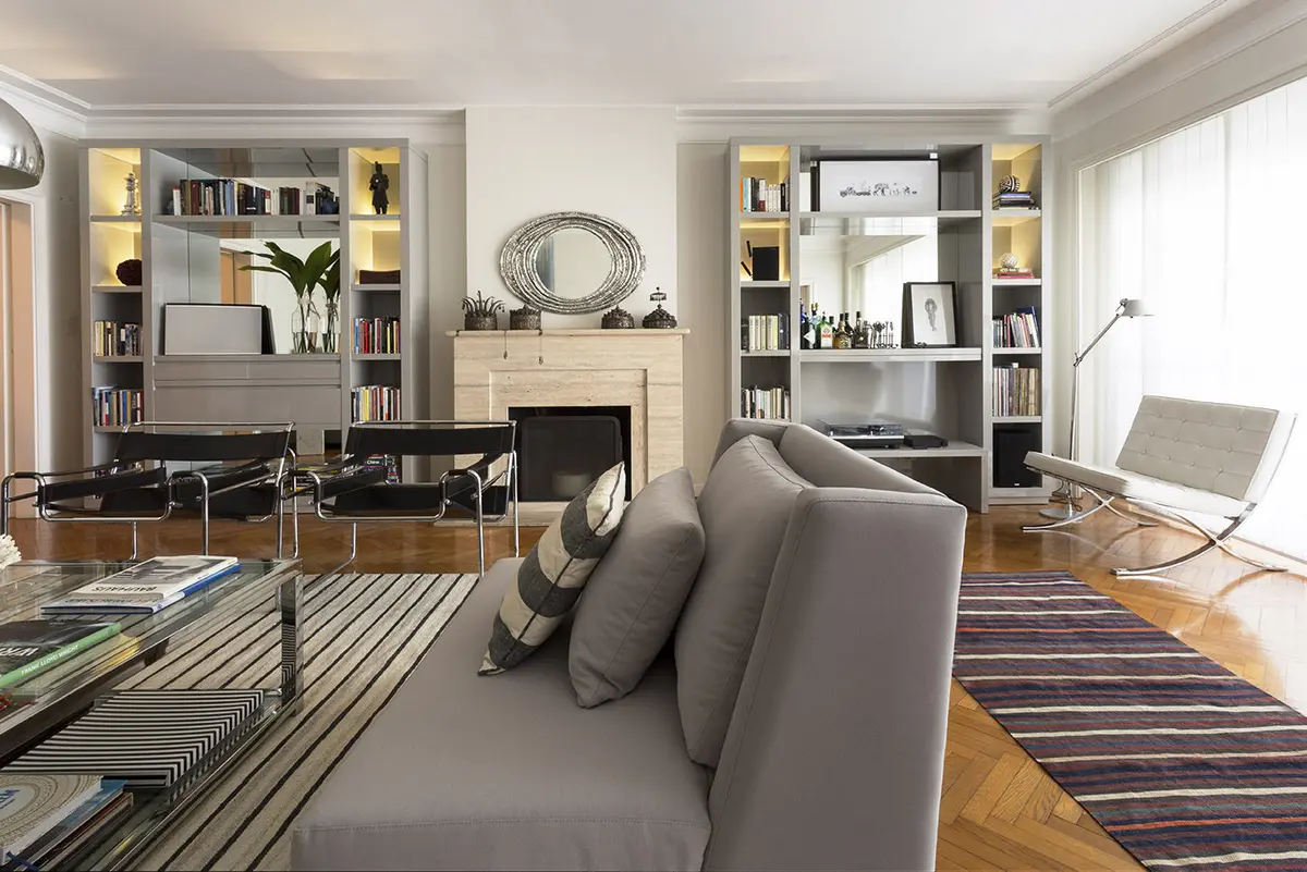 Sala de estar moderna com prateleiras embutidas e espelho redondo — projeto Obra Virrey del Pino, por M. Beatriz Gonzalez Zuelgaray, em Belgrano