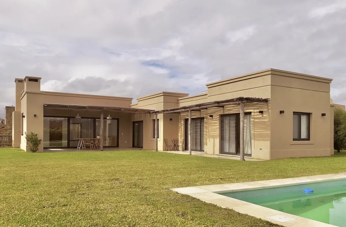Fachada moderna com piscina e pérgola de madeira em um amplo jardim — projeto Santa Teresa Villanueva 2, por Marconi Silva Arquitectos, em Benavidez