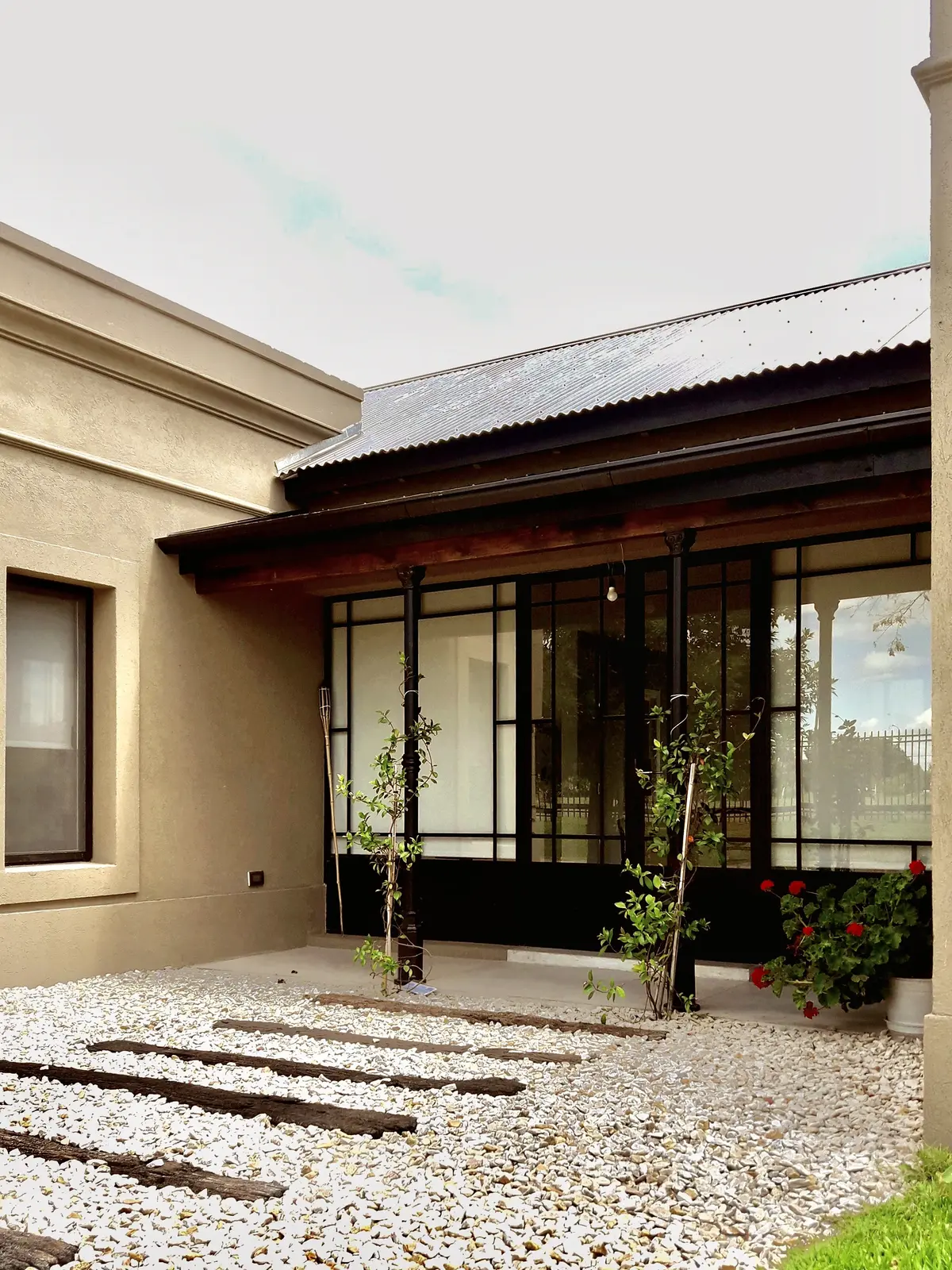 Pátio moderno com seixo branco, degraus de madeira e pérgola de metal — projeto Los Jazmines Pilar del Este, por Marconi Silva Arquitectos, em Pilar del Este