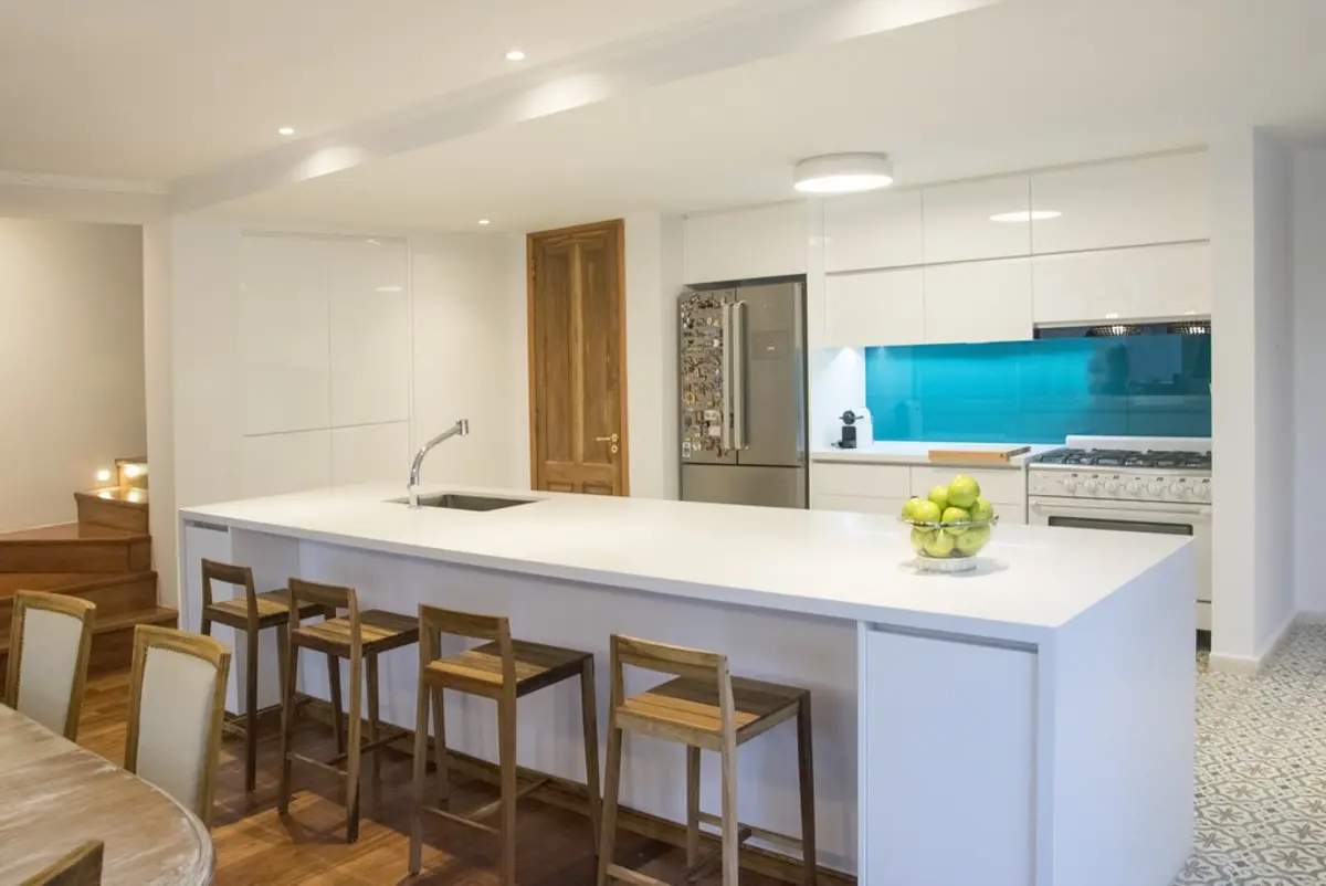 Cozinha moderna com ilha grande e cadeiras de madeira — projeto Casa Estilo Francés, por Estudio Fernandez Long & asoc., em Martínez