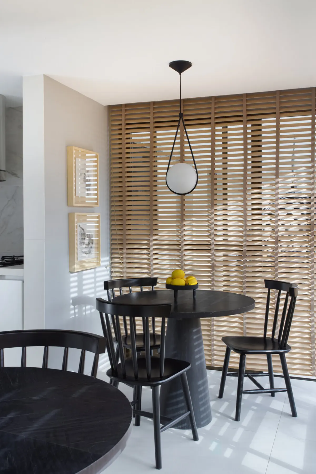 Comedor moderno con mesa negra, sillas y luz colgante frente a celosia madera — proyecto Decorado Latitud, por Studio Ro-ca