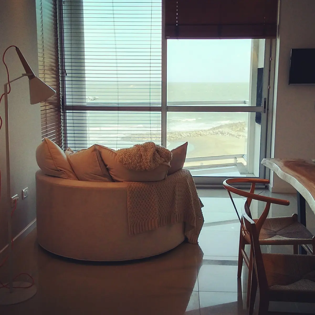 Living moderno con vista al mar, sillón redondo y lámpara de arco — proyecto Departamento MH, por Vicky Hurrell, en Mar del Plata