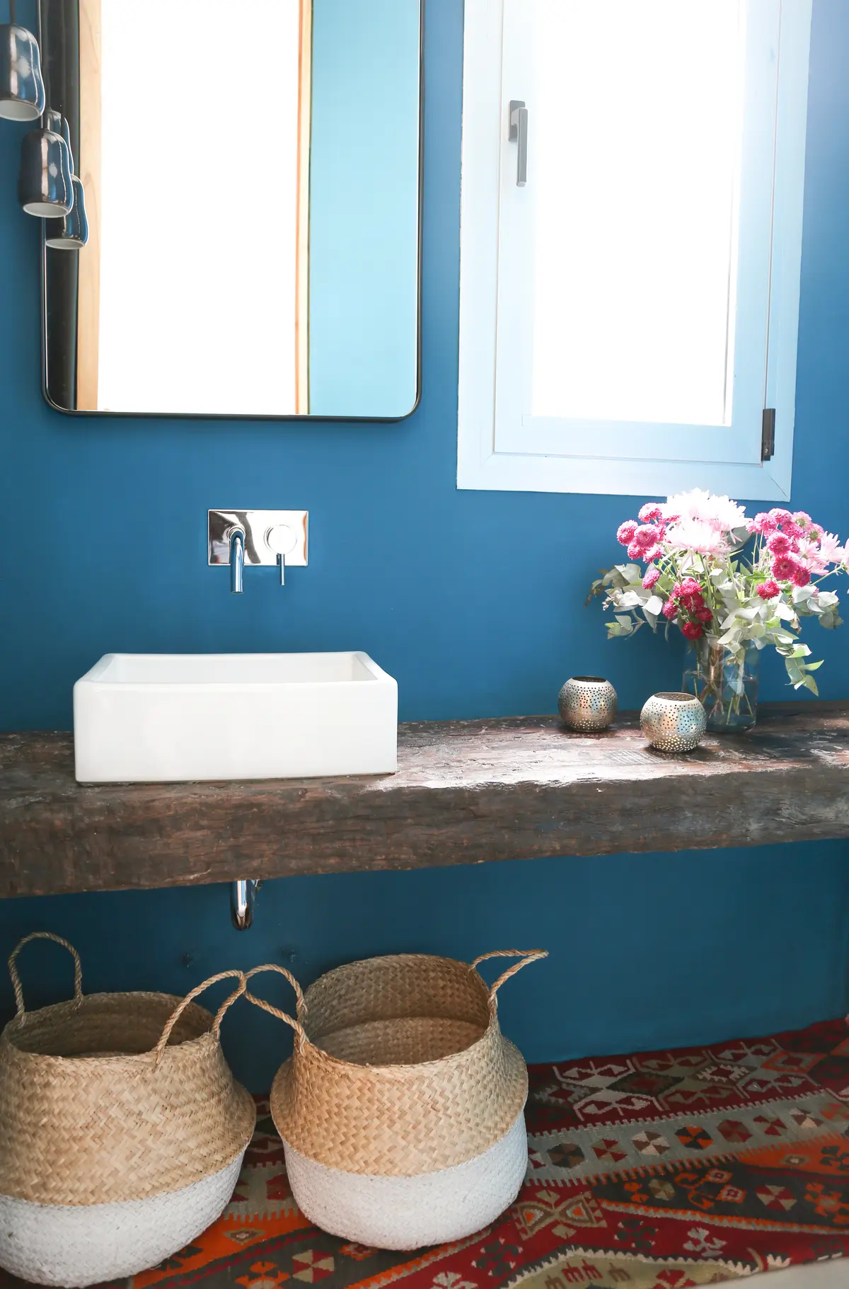 Baño azul con lavabo de cerámica sobre madera y cestas de mimbre — proyecto Proyecto San Isidro, por Olivia D, en San Isidro