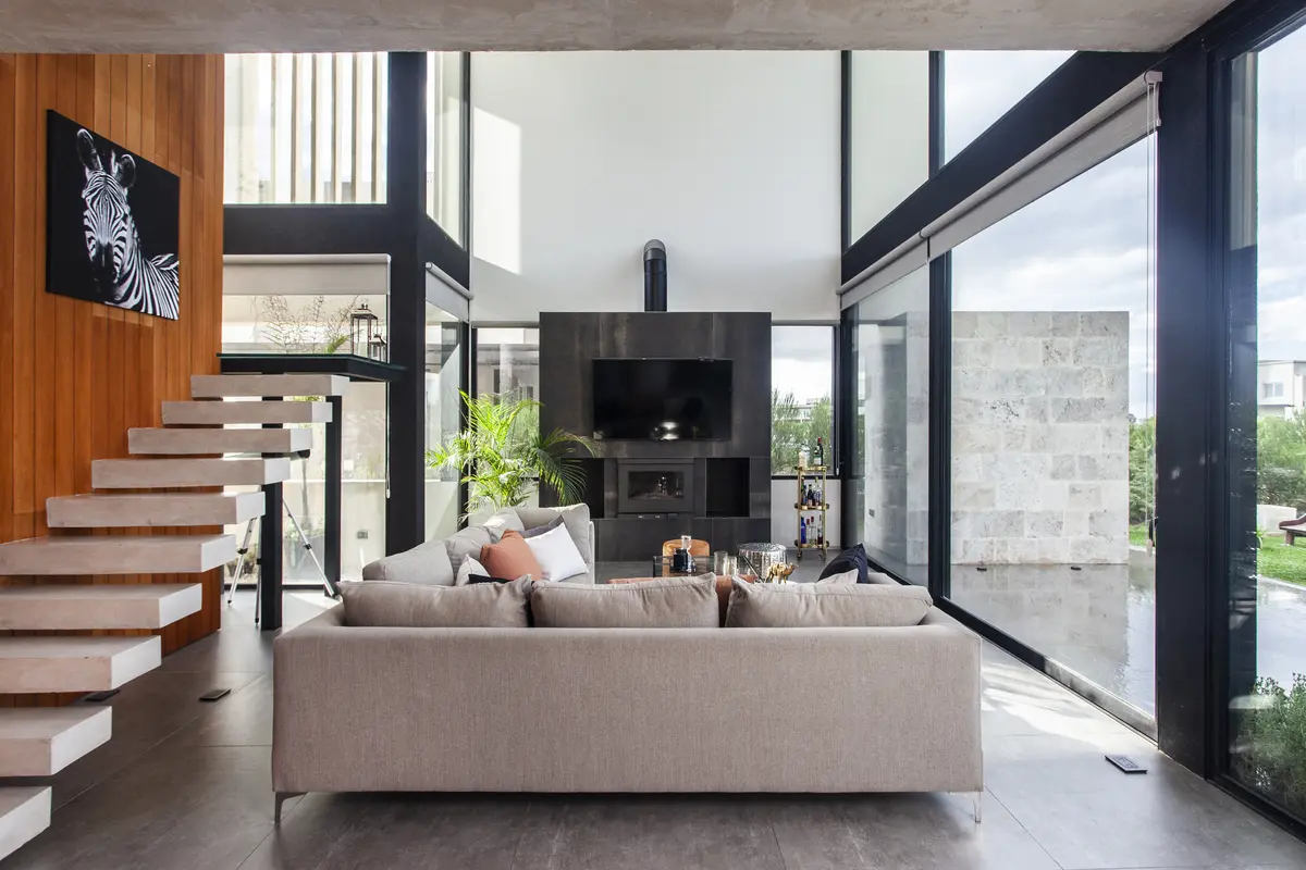 Sala moderna com pé-direito duplo e escada flutuante — projeto Casa BJM, por Vanguarda Arquitectos, em Belén de Escobar
