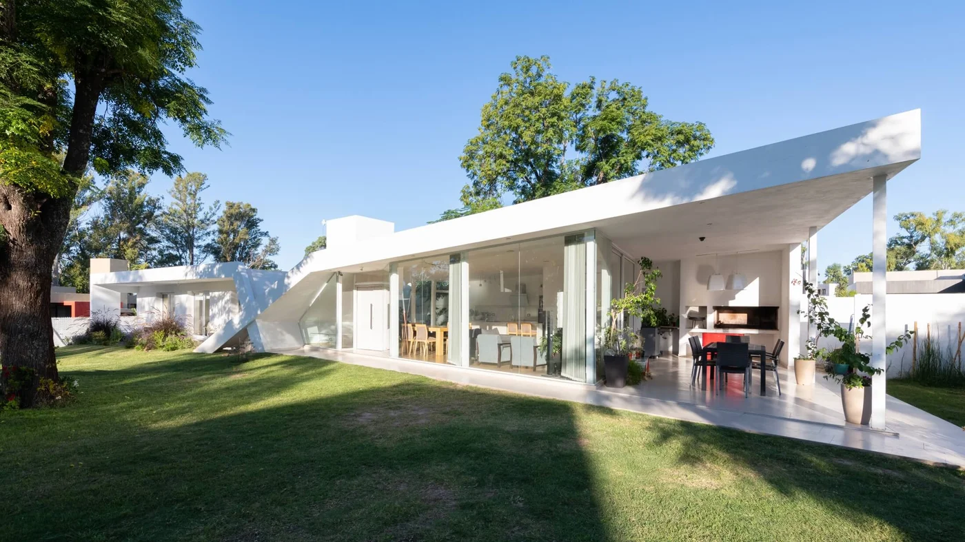 Casa moderna blanca con galería cubierta, jardín y grandes ventanales