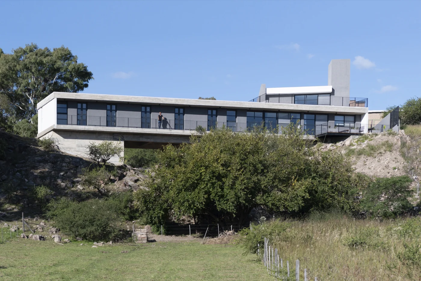 Casa moderna de hormigón con grandes ventanales y líneas horizontales.