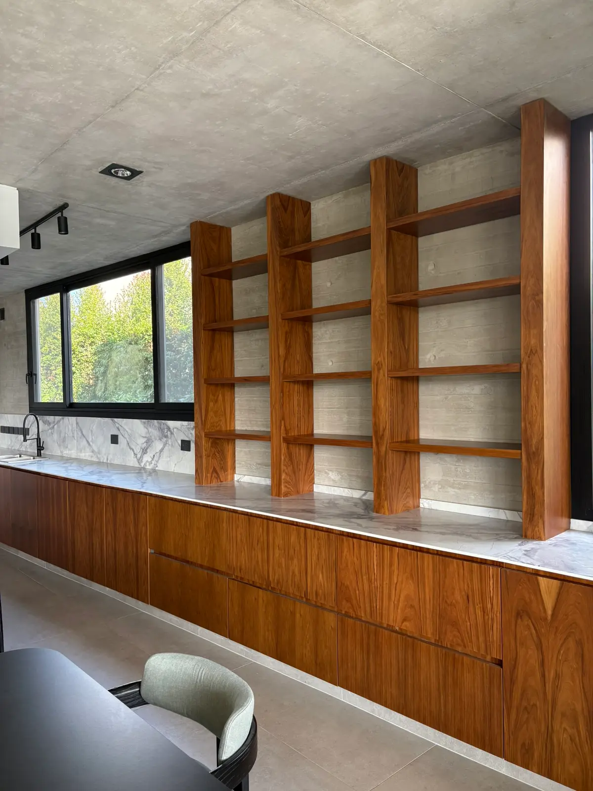 Cozinha moderna com prateleiras de madeira e detalhes em concreto aparente — projeto Carpinchos - Estudio Gambotto, por ABEJA CONCEPT, em Nordelta