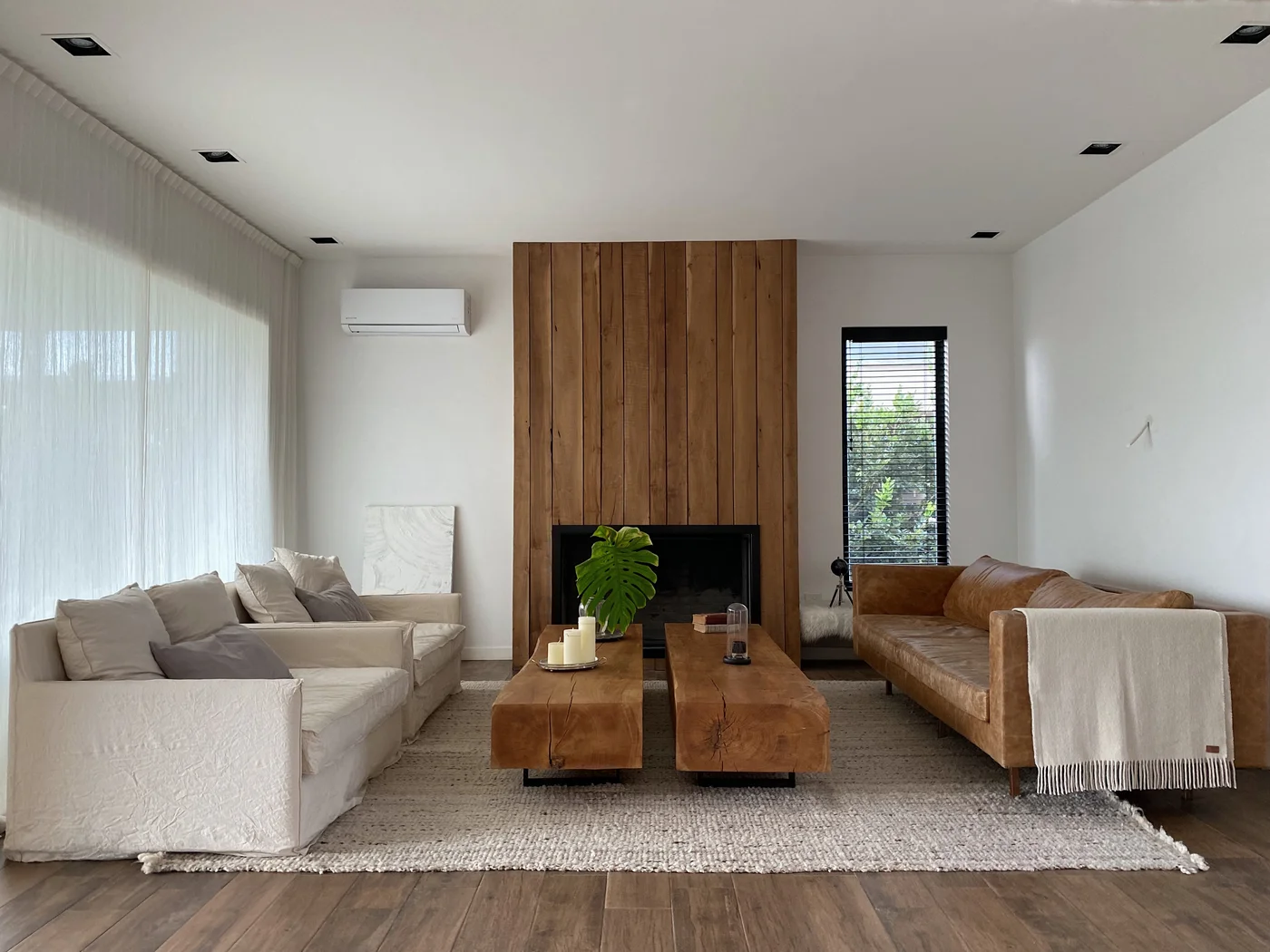 Living moderno con chimenea de concreto y muebles beige.