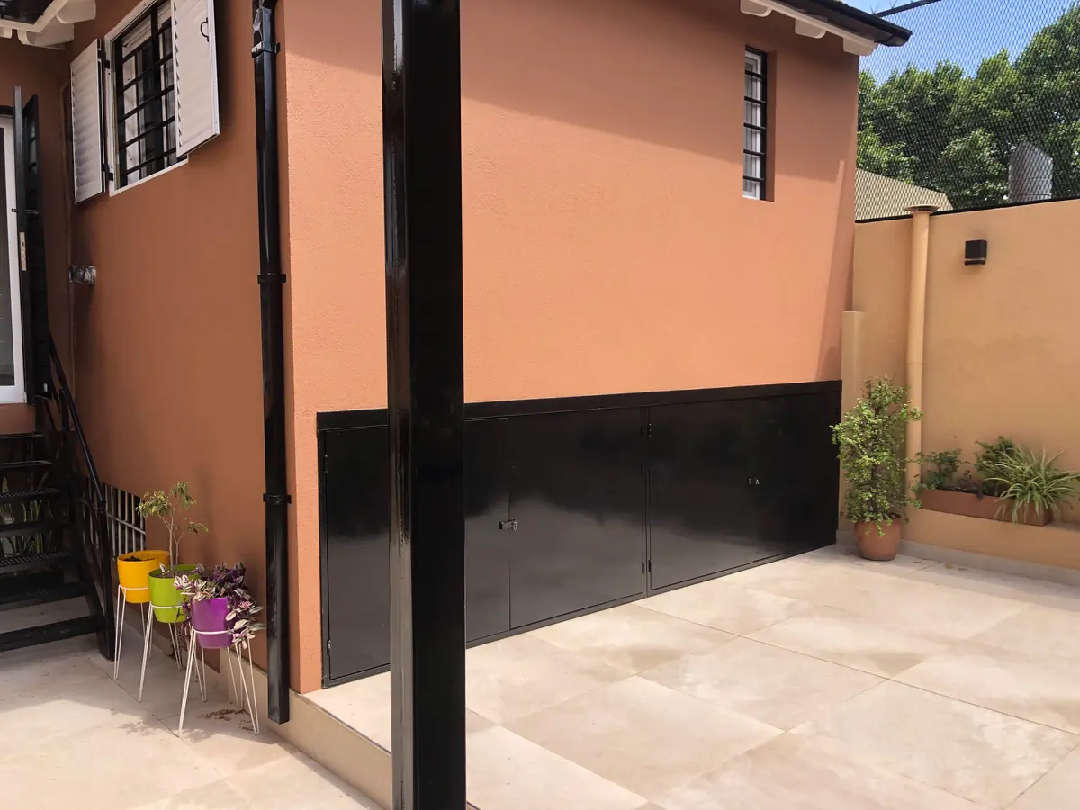 fachada moderna com porta de garagem preta e detalhes em terracota — projeto Marcelo & Majo, por Costantini studio, em Buenos Aires
