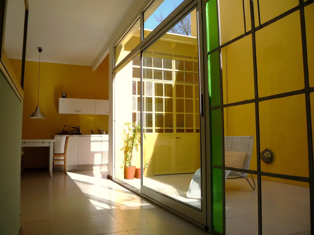Cocina moderna integrada a living con patio interno y paredes amarillas — proyecto Casa Thomas, por Estudio Dante Fiorenza, en La Plata