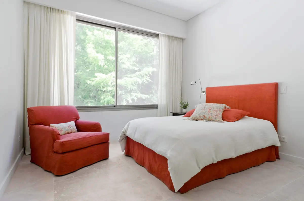 Quarto moderno com ampla janela para floresta e toque de cor bordô — projeto Casa P, por Estudio Dado, em San Isidro