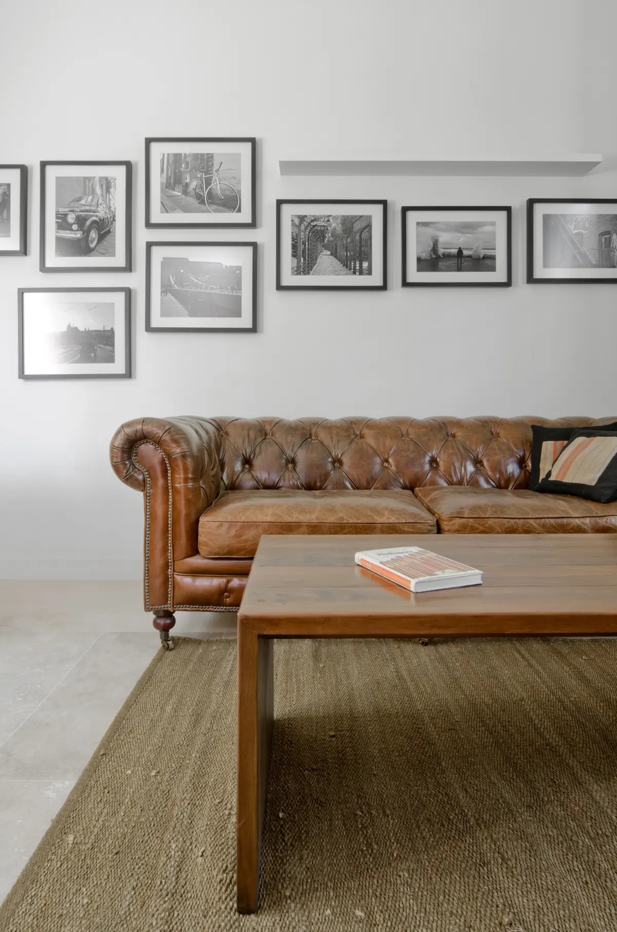 Sala com sofá chesterfield de couro, mesa de madeira e quadros — projeto Casa P, por Estudio Dado, em San Isidro