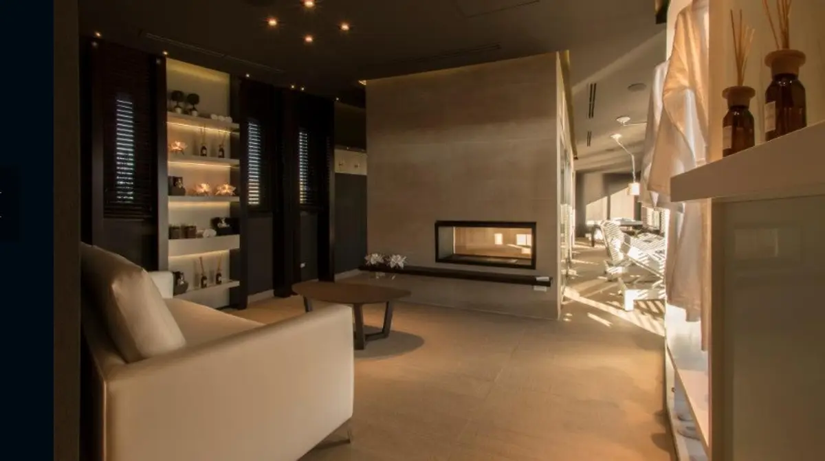 Living moderno con chimenea minimalista y sillón de tela beige — proyecto Spa Ville St Germain, por Estudio de Int Diana Gradel, en Cariló