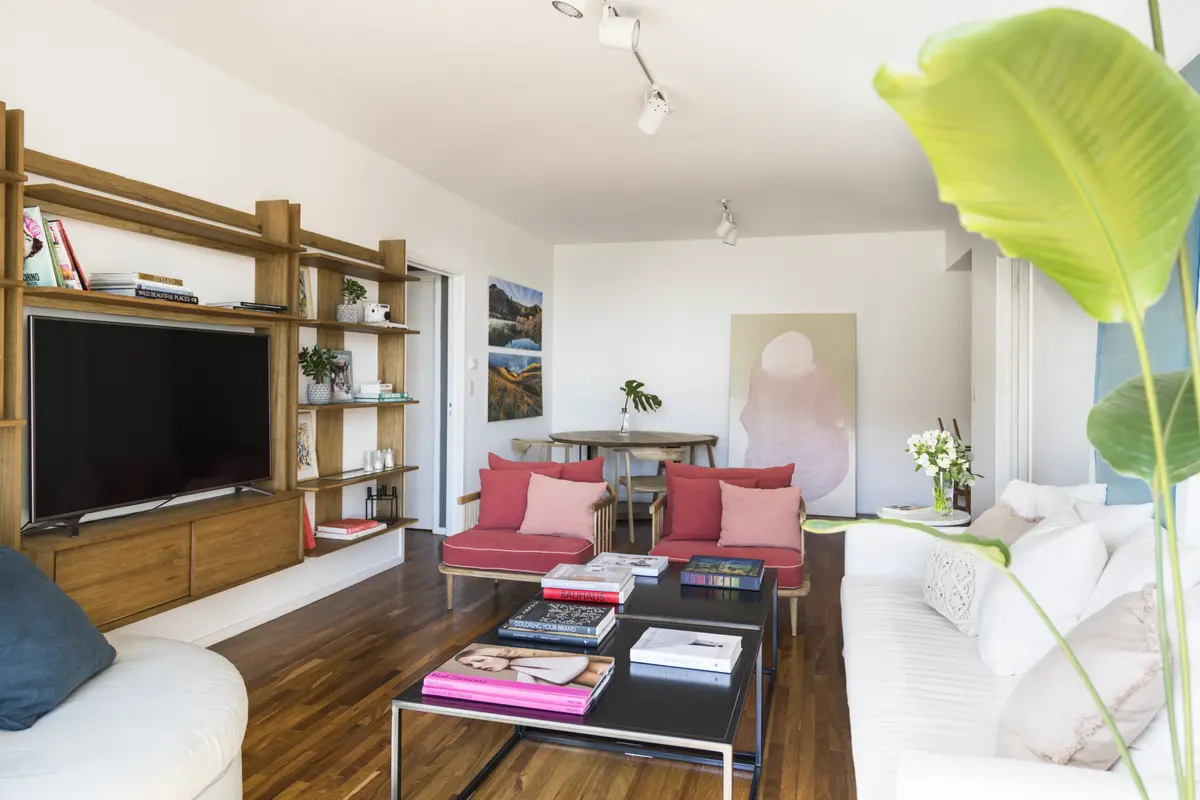 Sala de estar moderna com estantes de madeira e poltronas vermelhas — projeto Proyecto Don Bosco, por URBANO estudio, em San Isidro