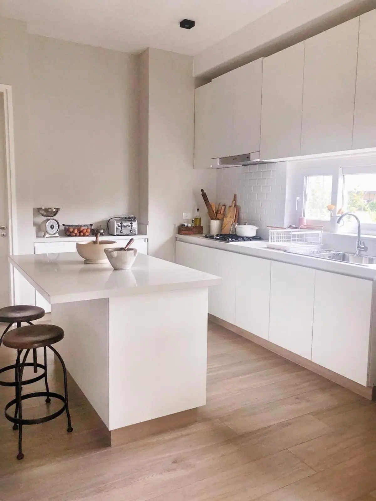 Cozinha escandinava moderna com ilha branca e piso de madeira clara — projeto CASTAÑOS, NORDELTA, por Greschek Obras, em Nordelta
