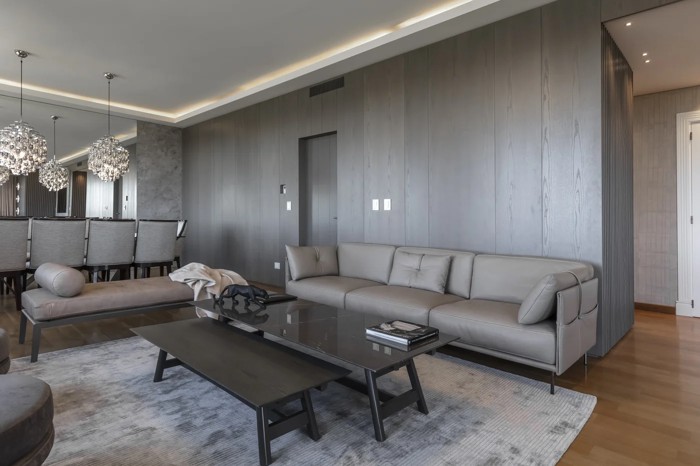 Living moderno con sofá modular, paredes de madera y luces colgantes