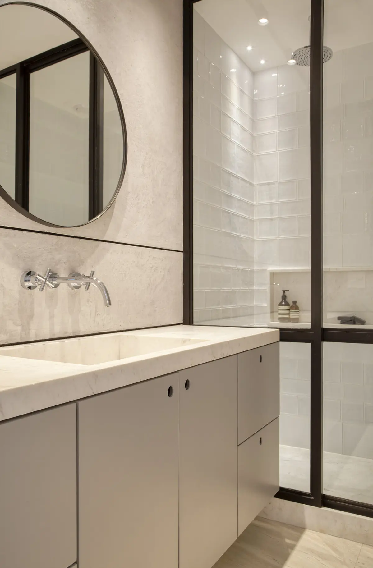 Baño moderno con mesada blanca, espejo oval y ducha con marco negro — proyecto PS House, por Studio Ro-ca