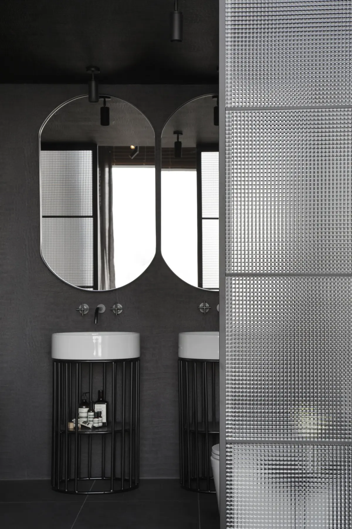 Bano minimalista con espejo redondeado y mesada blanca sobre pared negra — proyecto Casa COR 2017, por Studio Ro-ca