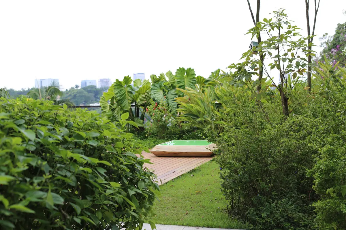 Jardín contemporáneo con deck de madera y vegetación exuberante — proyecto Residência MP, por Gil Fialho