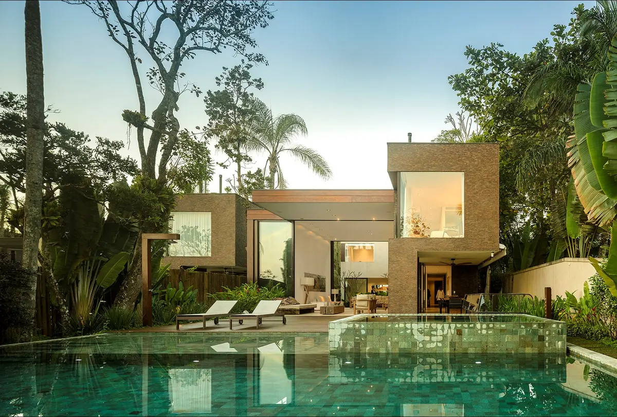 Casa contemporánea con pileta verde rodeada de vegetación tropical — proyecto West Whales, por Gil Fialho