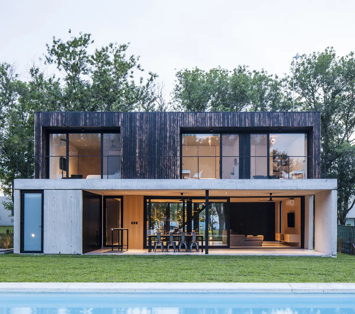 Casa moderna con fachada de madera oscura, vidrio y piscina — proyecto Black House, por V2 Arquitectos, en City Bell