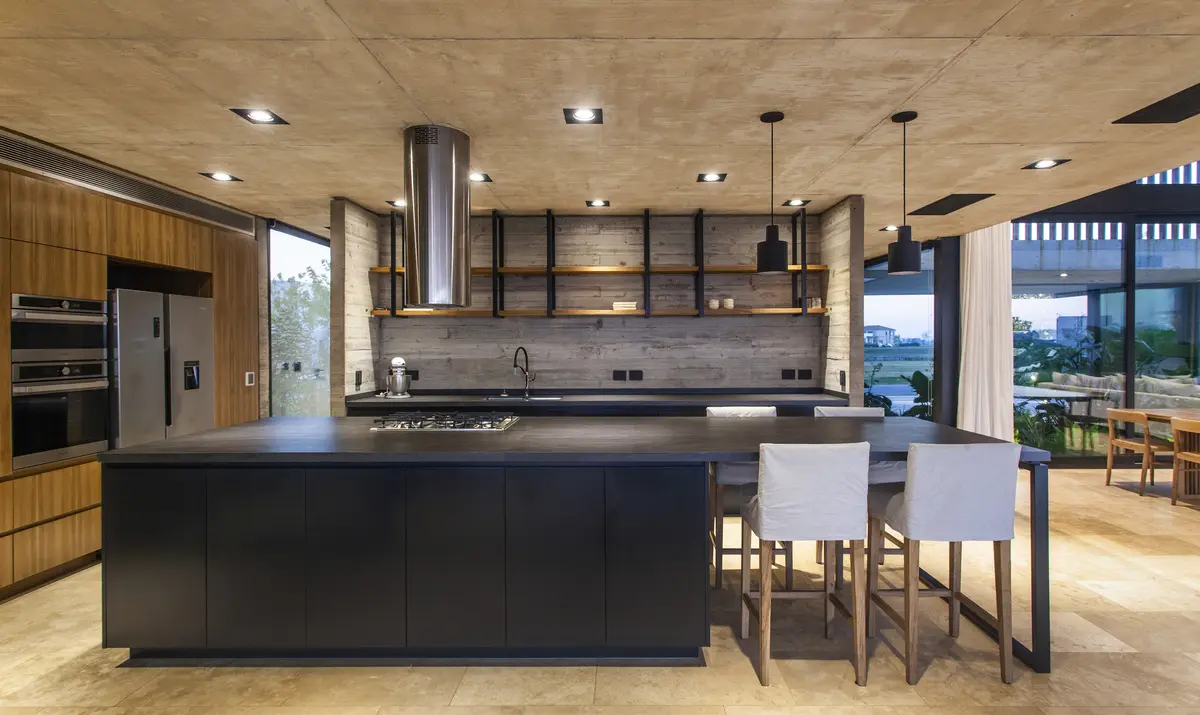 Cozinha moderna industrial com ilha preta e teto de concreto — projeto Casa FG, por DIPA arquitectos