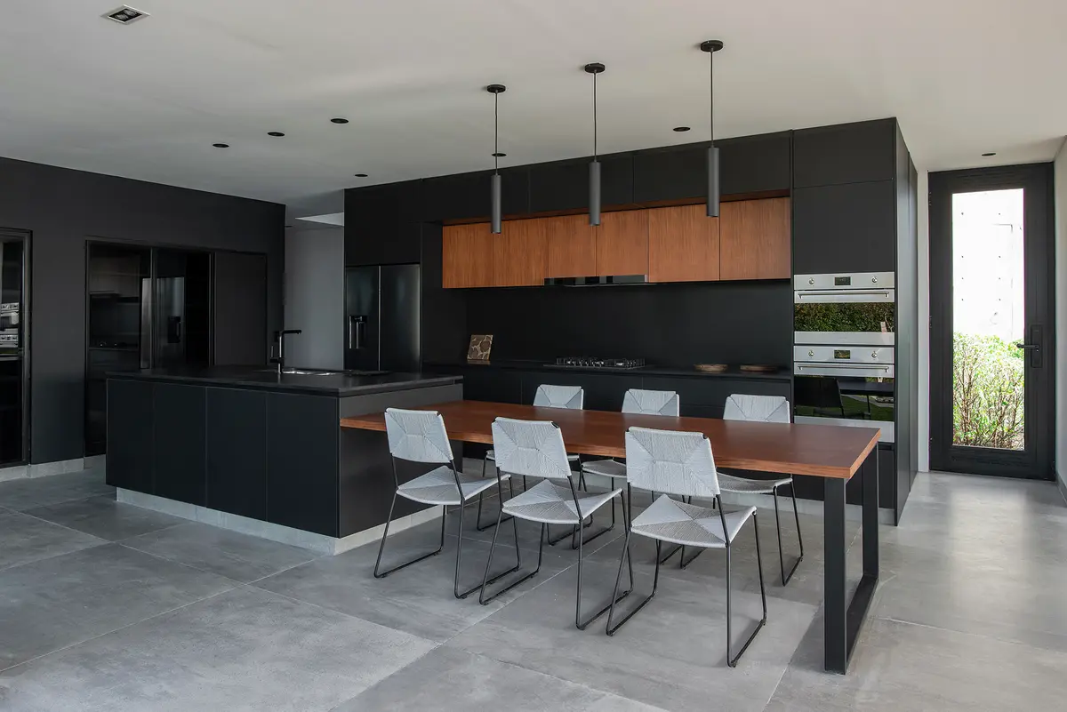 Cocina moderna minimalista con isla negra y mesa de madera — proyecto CASA MUELLES, por GMARQ, en Escobar