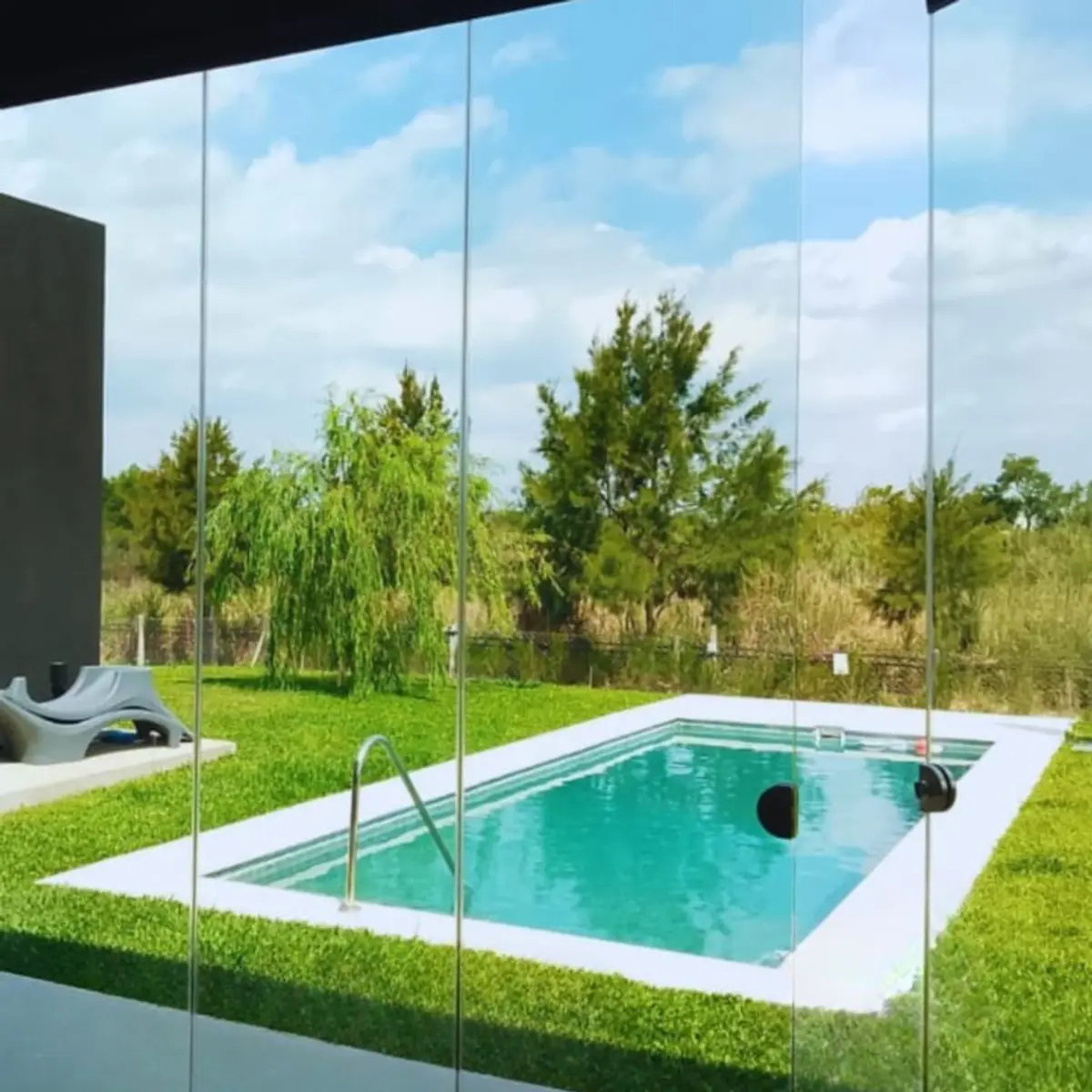 Pileta rectangular moderna con vidrieras panoramicas y jardin natural — proyecto EL NAUDIR, por CERRAMIENTOS PANORAMICOS, en Belén de Escobar